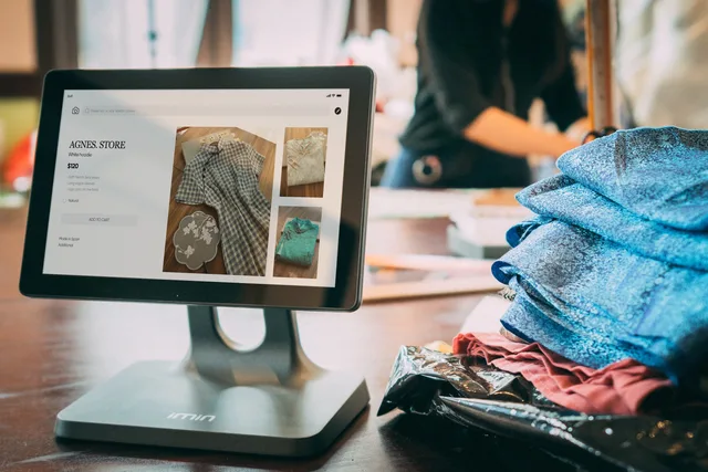 A digital point-of-sale system in a small fashion boutique with clothes displayed on a tablet. Betalingsløsninger til erhverv: MobilePay, betalingsgateway og fakturabetaling